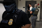 A migrant is detained by federal immigration officers at U.S. immigration court