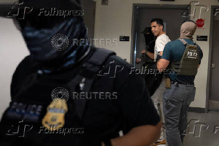 A migrant is detained by federal immigration officers at U.S. immigration court
