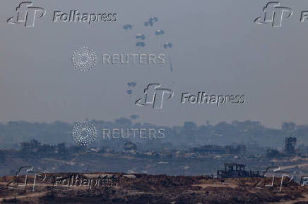 An aircraft drops humanitarian aid packages over the Gaza Strip, as seen from Israel
